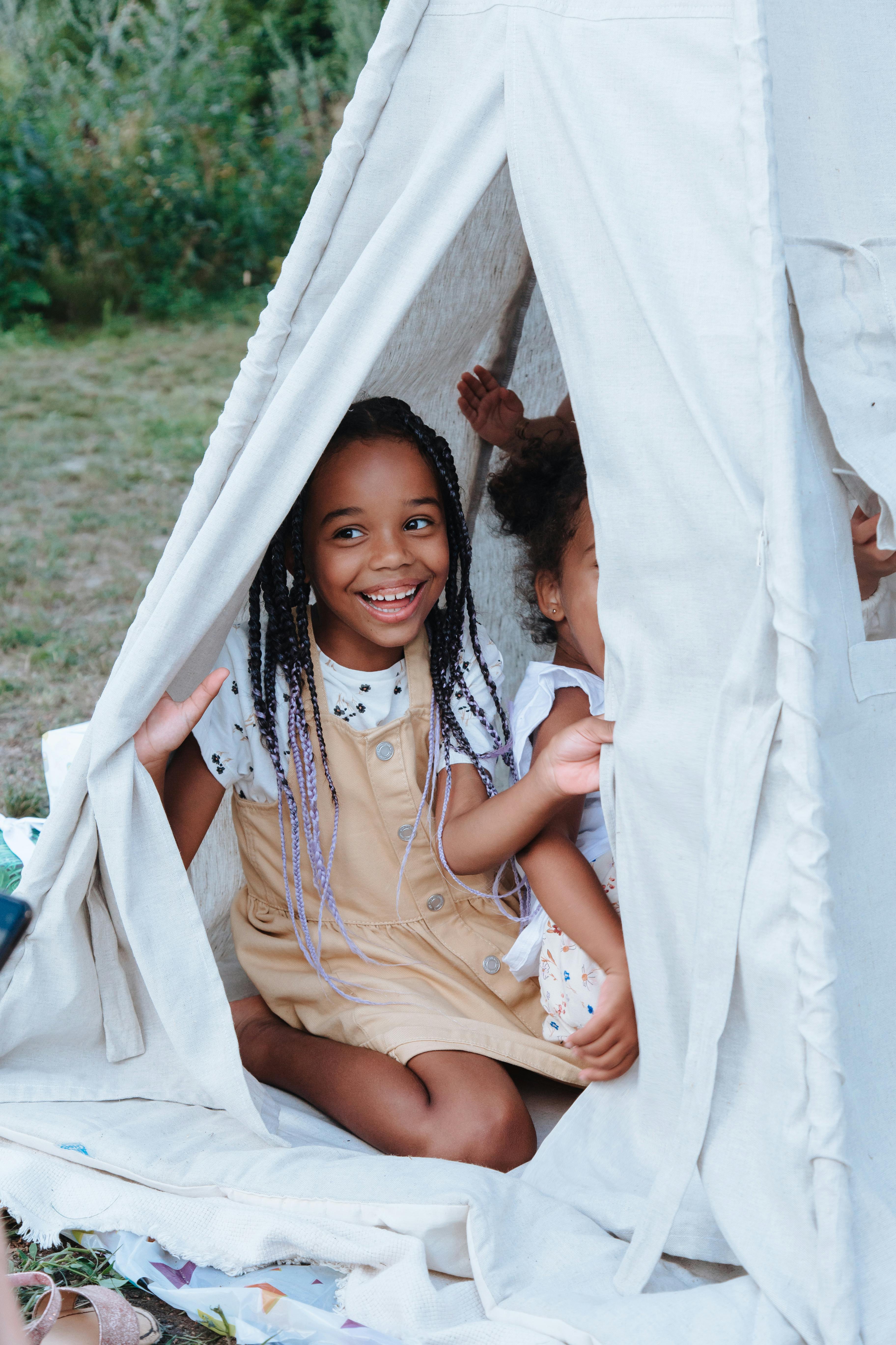 Smiling girls playing inside a canvas tent at a summer camp